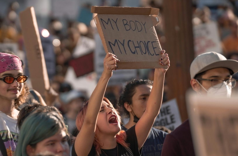 A woman passionately holding up a sign that reads “My Body My Choice” at a rally, surrounded by other protestors advocating for reproductive rights.