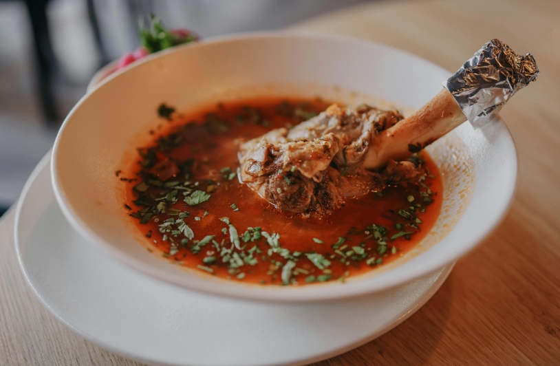 Reddish broth with beef on bone extending from the bowl.