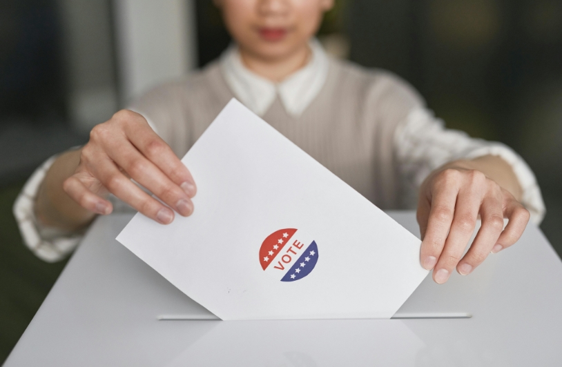 A woman places a ballot into a voting box.